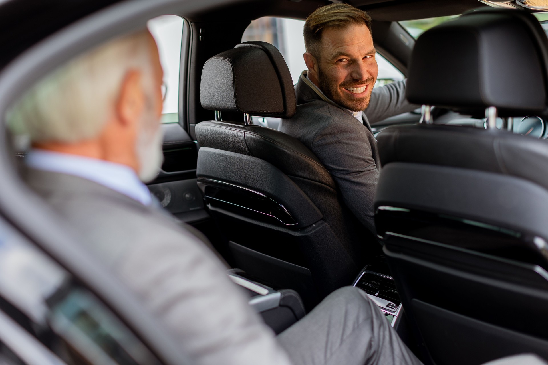 Smiling passenger engaging in friendly conversation with driver inside a modern car
